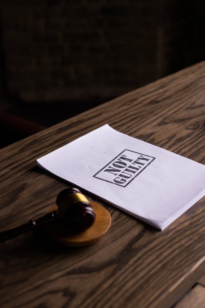 A legal gavel next to a Not Guilty document on a wooden table, symbolizing justice.